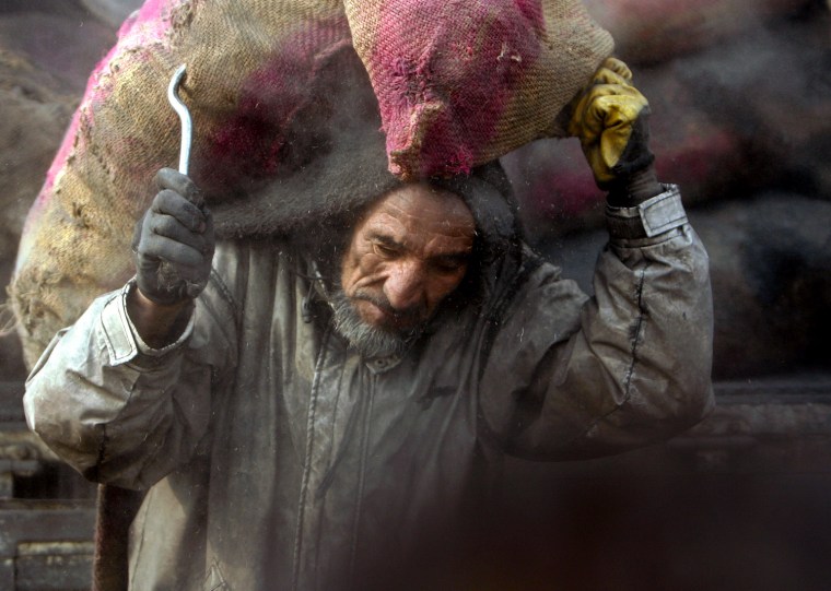 Image: An Afghan man carries a sack of coal at a WFP distribution site for winter supplies in Kabul